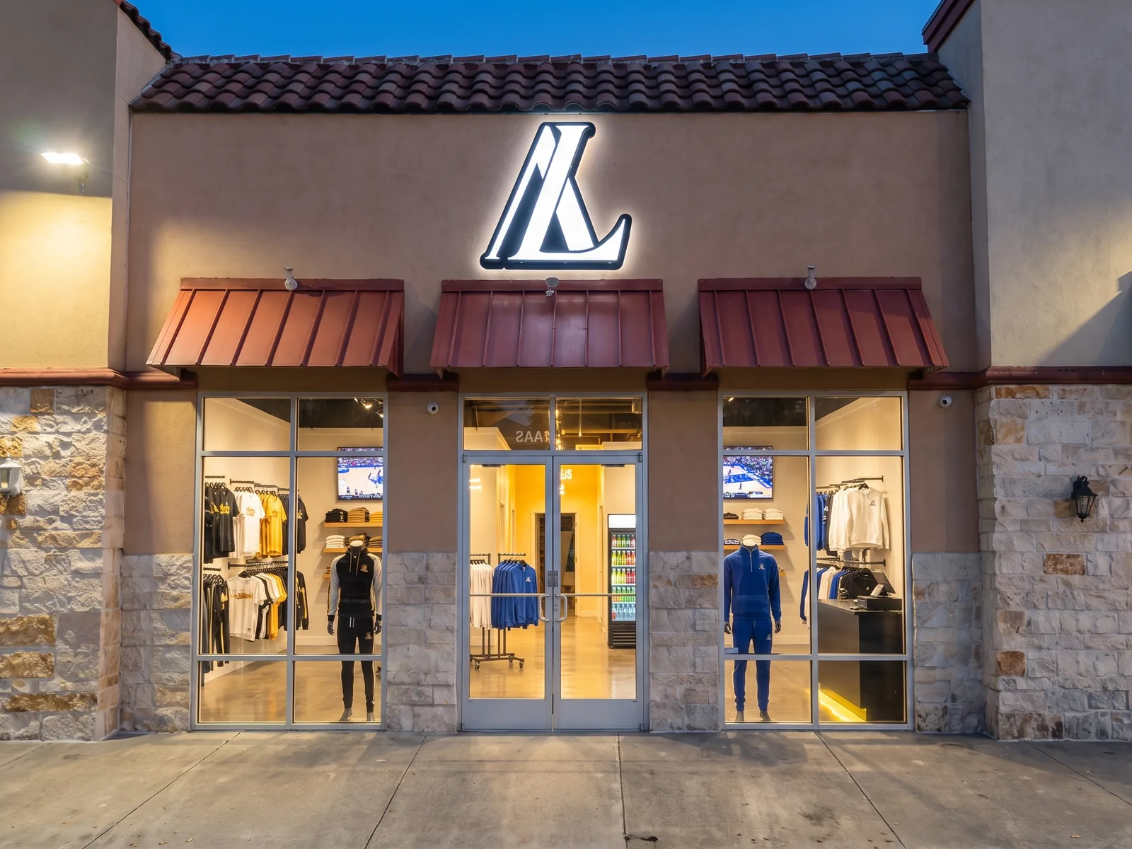 Allegiance Lifestyle storefront on Donnelly Ave: tan stucco, three red metal awnings, and the lit L monogram sign above the glass doors